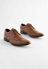 Brązowe skórzane buty formalne z klapkami, z perforowanymi detalami i gładkim wykończeniem, w komplecie z niskim czarnym obcasem.