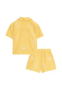 Geel katoenen set met een kortemouwen shirt en shorts, voorzien van witte geborduurde patronen van ananassen, schelpen en palmbomen.