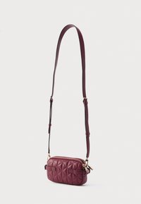 Borsa a tracolla in pelle bordeaux trapuntata con chiusura a zip, tracolla regolabile e dettagli in metallo tono oro. Design contemporaneo e forma compatta.