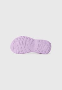 Vaalean violetti kumipohja, jossa on teksturoitu pinta, urat ja logo. Suunnittelu tukee pitoa erilaisilla maastoilla.