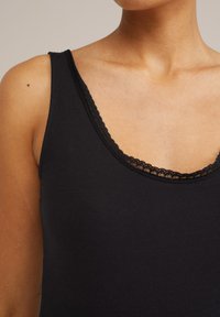 Czarny top na ramiączkach z okrągłym dekoltem, ozdobiony koronkowym wykończeniem. Wykonany z miękkiego materiału, ma szerokie ramiączka i dopasowany fason.