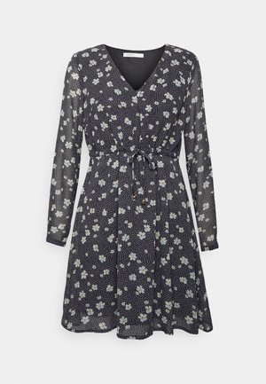 Vestido com padrão floral em azul marinho, com mangas longas, decote em V, cintura ajustada e tecido leve com flores brancas e azul claro.