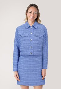 Blauwe tweed cropped jack met een kraag, knopen aan de voorkant en twee borstzakken, gecombineerd met een bijpassende rok. Gestructureerde stof.
