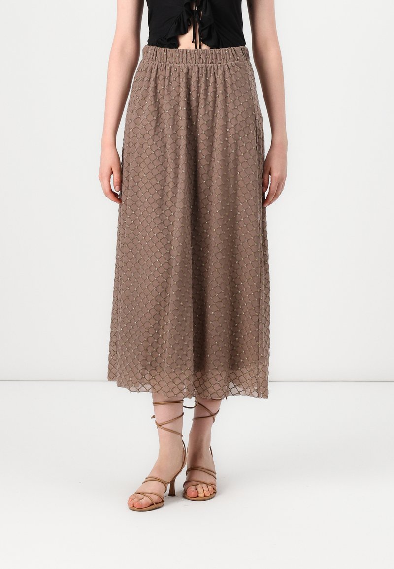Jupe midi marron avec un motif texturé de losanges en relief. Taille élastique, tissu léger et silhouette fluide. Accompagnée de talons à lanières.