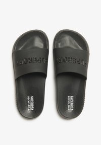 Zwarte slip-on sandalen met een dikke band die is geprint met "SUPERDRY." Gemaakt van een gestructureerd materiaal met een comfortabele binnenzool en een gerecycled etiket.