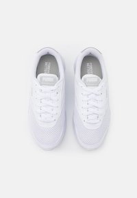 Chaussures de sport blanches avec une tige en maille, un embout rond et des lacets plats. Elles présentent une semelle rembourrée et un motif texturé sur les côtés.