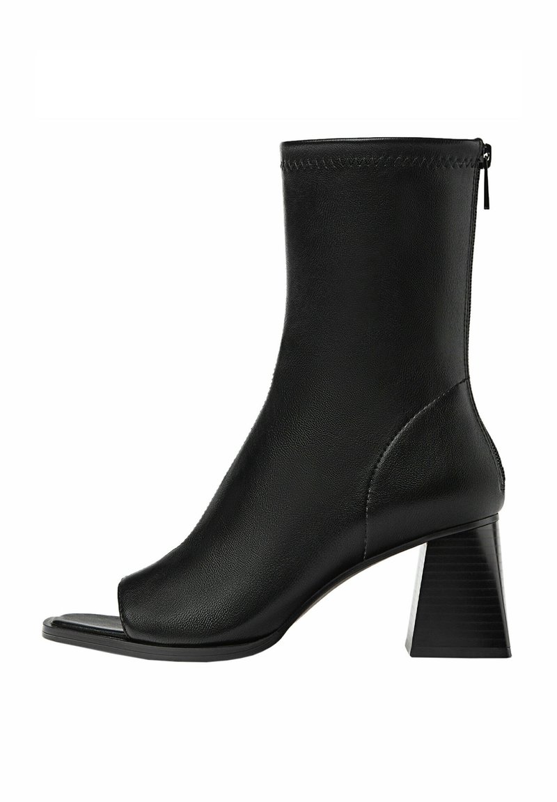 Botte mi-mollet en cuir noir à bout ouvert, talon bloc et fermeture éclair arrière, design moderne et épuré.