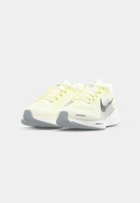 Baskets de sport jaune clair avec une tige en mesh respirant, accents gris et semelle texturée. Équipées d'un système de laçage et de détails de logo.