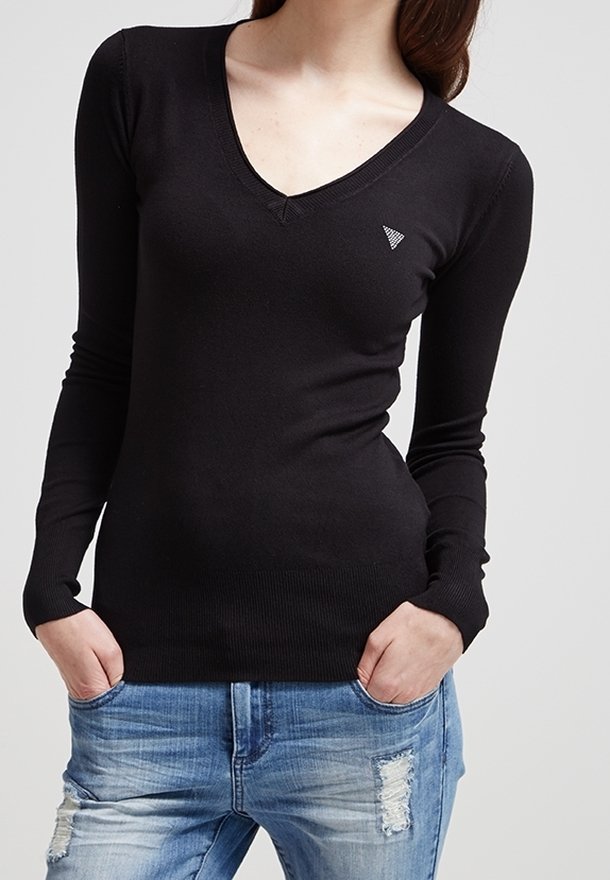 Černý dlouhý rukáv V-krk svetr vyrobený z měkkého a elastického materiálu. Na levé hrudi má malé trojúhelníkové logo. V kombinaci s ošuntělými modrými džíny.