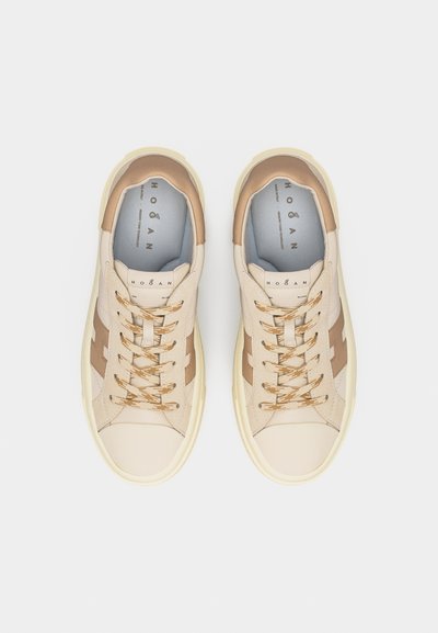 Baskets beige et marron clair à coupe basse avec lacets à motifs, embout rond et logo de la marque sur le côté et la languette, vues de dessus sur fond blanc.