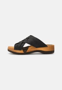 Svart vävd slidesandal med en strukturerad ovandel, en trälik plattform och gummiyttersula med ett mönstrat grepp.