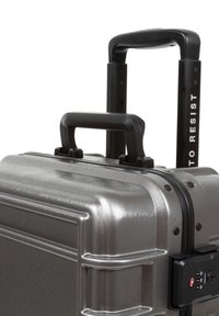 Gray metallic hard-shell suitcase with textured surface, retractable handle, and TSA-approved combination lock.