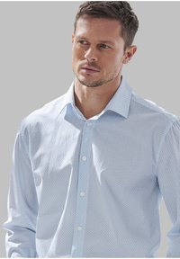 Camicia azzurro chiaro con bottoni, caratterizzata da un sottile motivo geometrico. Il tessuto è morbido, con una vestibilità casual e colletto standard.