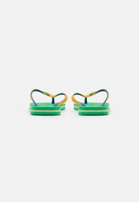 Green rubber flip-flops with yellow straps, featuring a textured footbed. The straps are curved and have a logo accent in yellow.