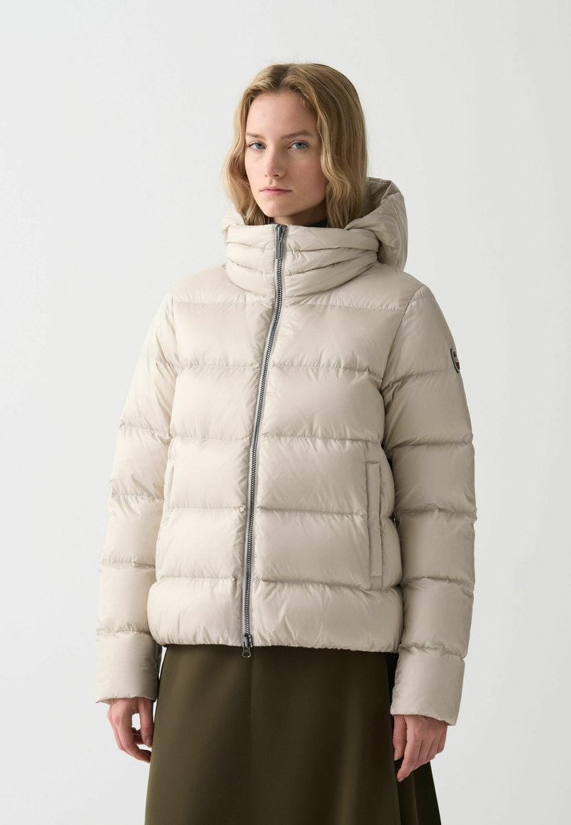 Puffig beige jacka med hög krage och dragkedjestängning, med horisontella vadderade sektioner och sidofickor. Slät, glänsande material.