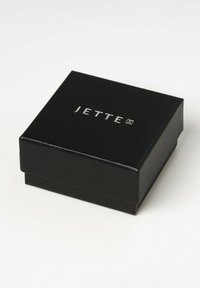 Scatola per gioielli rettangolare nera con una finitura testurizzata, caratterizzata dal logo in rilievo "JETTE" in argento sulla parte superiore.