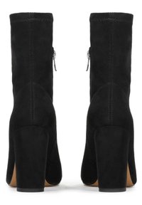 Botine negre din suede la glezna, cu toc bloc înalt, dotate cu fermoare laterale și detalii cusute pe cusături. Textură netedă cu vârf rotunjit.