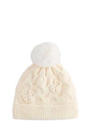 Strikket hue i cremet farve med ribbet kant, kabelmønster og to sløjfedetaljer. Afsluttet med en fluffy hvid pompon på toppen.