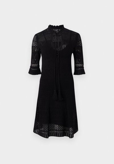 Schwarzes Strickkleid mit hohem Ausschnitt, dreiviertellangen Ärmeln mit Rüschensaum und einem strukturierten Muster. Inklusive einem Band mit Quasten.