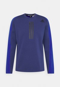 Maglietta atletica a maniche lunghe di colore blu scuro con pannelli laterali in blu chiaro a contrasto. Presenta un design a tre strisce nere sul davanti. Tessuto testurizzato.