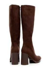 Botas de ante marrón hasta la rodilla con tacón plano, que cuentan con una cremallera lateral y un acabado suave. El tacón es ancho y mide aproximadamente 3 pulgadas de altura.