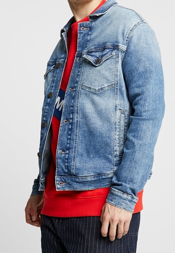 Jeansjacka i ljusblått med knäppning, två bröstfickor och en kontrasterande röd sweatshirt under, med horisontella ränder.