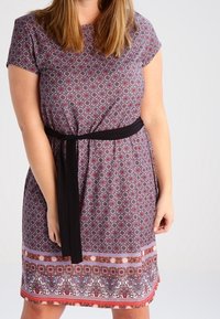 Vestido corto de manga corta en púrpura con un cinturón negro. Presenta patrones florales y acentos con franjas en el dobladillo en tonos rojos y azules.