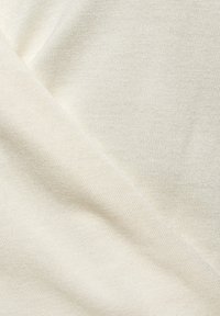 Tejido texturizado de color beige claro con un patrón de punto fino, mostrando un leve brillo, doblado para mostrar profundidad y capas.