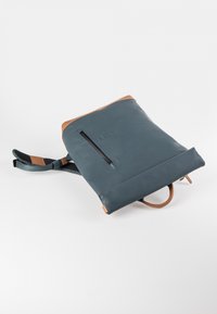 Blauwe waterdichte rugzak met bruine leren accenten, voorzien van een voorste ritsvak en gevoerde schouderbanden voor comfort en ondersteuning.