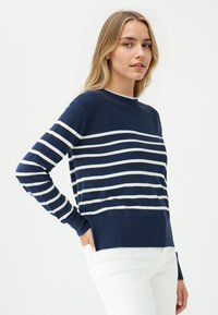 Sweter w marynarskie paski z białymi poziomymi pasami, okrągły dekolt, długie rękawy, ściągacze na mankietach i u dołu, wykonany z miękkiego materiału dzianinowego.
