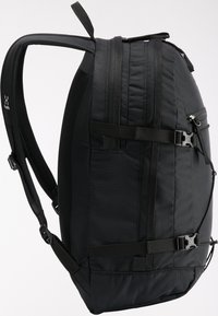 Mochila negra con un diseño curvado. Fabricada en tejido resistente, cuenta con correas ajustables y un bolsillo lateral con cierre de hebilla.