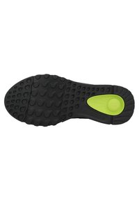 Suola di scarpa in gomma nera con motivi di trazione arrotondati, una zona accentuata di colore verde e scanalature per la flessibilità. Logo del marchio visibile.