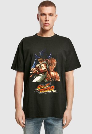 Schwarzes Baumwoll-T-Shirt mit einem bunten "Street Fighter"-Grafikdesign, das zwei Charaktere zeigt. Rundhalsausschnitt, kurze Ärmel, lockere Passform.