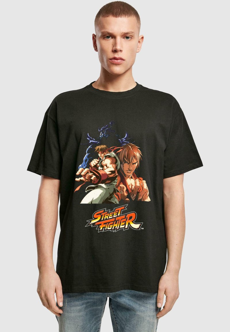 Black cotton t-shirt featuring a colorful "Street Fighter" graphic with two characters. Crew neck, short sleeves, relaxed fit.