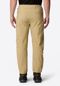 Beige outdoor pants made of lightweight fabric, featuring a straight leg design and side pockets. Logo displayed on the lower leg.