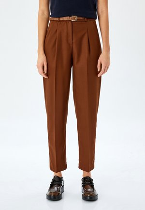 Brown, tailored trousers with pleats, featuring a fitted waistband and a belt. The fabric has a smooth texture, paired with black shoes.