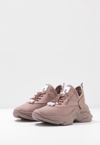 Baskets roses avec une tige en mesh, une semelle en caoutchouc et des lacets élastiques. Elles possèdent un col rembourré et une étiquette logo visible sur la languette.