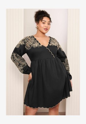 Crna haljina s dugim nabranim rukavima, koja ima zlatnu cvjetnu aplikaciju, ovratnik sa valovitim rubom i rašireni donji dio.