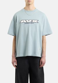 Jasnoniebieska, bawełniana, oversize'owa koszulka z krótkim rękawem i okrągłym dekoltem, z dużym haftowanym logotypem "AVX" oraz napisem "AVIREX DEPT."