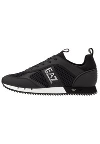 Sneaker nera con pannelli in rete, lacci e suola in gomma bianca. Presenta accenti geometrici e un dettaglio con il logo sul lato. Finitura testurizzata.