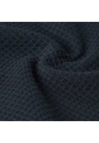 Primer plano de tela de punto texturizada en azul marino oscuro con un sutil patrón de gofre y pliegues suaves.