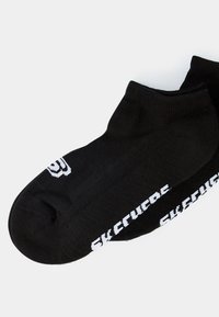 Chaussettes noires mi-mollet en matériau tricoté, avec du texte blanc sur les côtés. Design simple avec un bord côtelé pour un ajustement sûr.