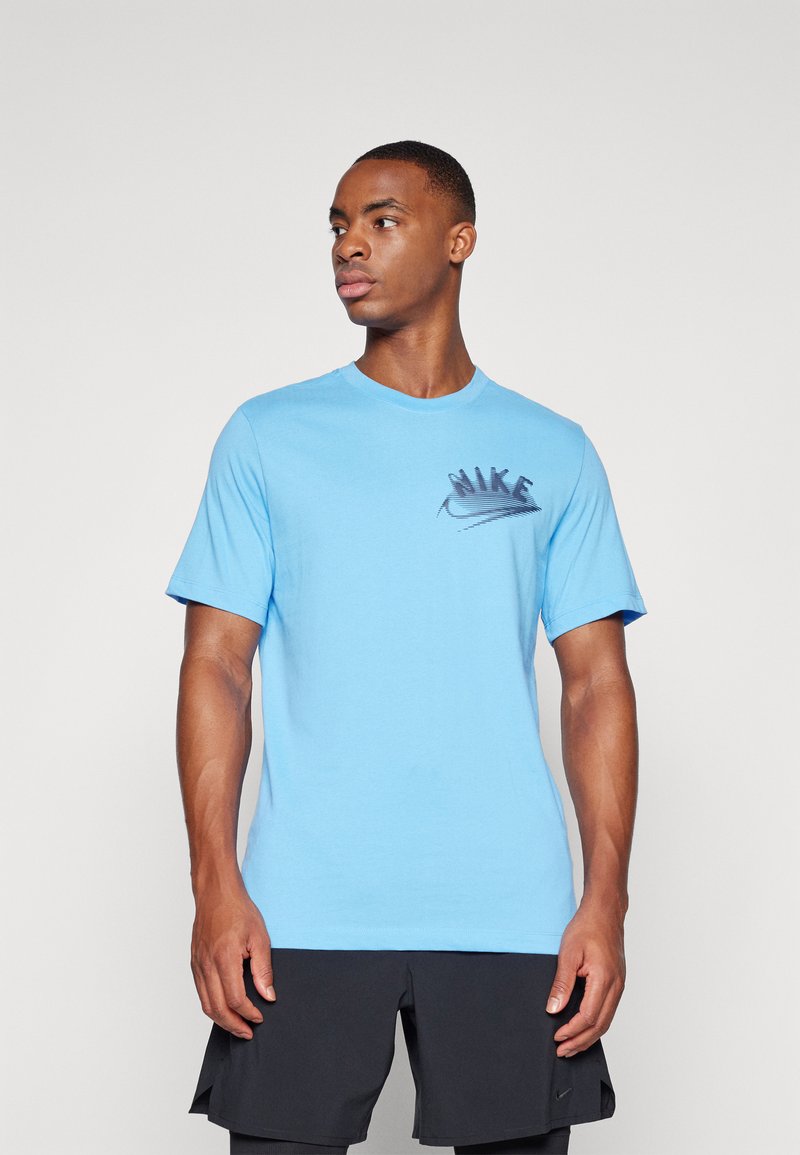 T-shirt in cotone blu chiaro con maniche corte, scollo rotondo e logo Nike nero sul petto. Texture liscia, design aderente.