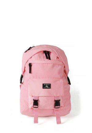 Sac à dos rose avec poche avant, boucles noires, fermetures éclair et une étiquette portant la mention "MINOTI Love to Explore" sur fond blanc.