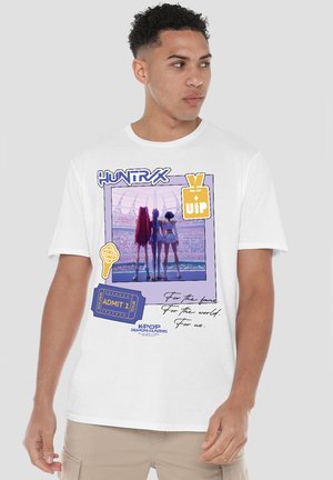 Man wearing white T-shirt with graphic of three K-pop characters on stage, VIP pass, ticket, and handwritten text.