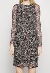 Genomskinlig långärmad klänning med ett geometriskt mönster i svart, rosa och grått. Har en rund halsringning och textil med en åtsittande silhuett.