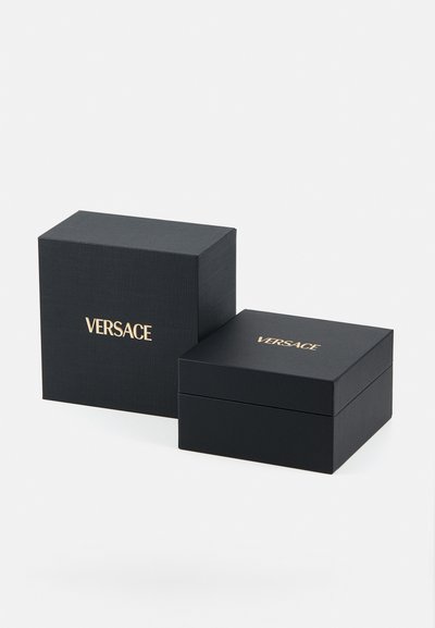 Čierne prezentačné krabičky s textúrovaným povrchom, zlatý logo "VERSACE" na vrchu, štvorcový tvar, dizajn s jedným vekom, naskladané pod uhlom.