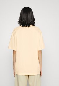 Kortærmet, løst siddende t-shirt i blødt pastellgul bomuld, med en lige kant og minimalistisk design. Ensfarvet uden synlige grafikker.