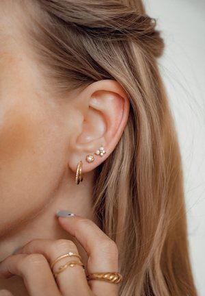 Los pendientes de oro y perlas incluyen un pequeño aro, un arete de perla y un diseño floral con múltiples perlas pequeñas, todo ello sobre un fondo claro.