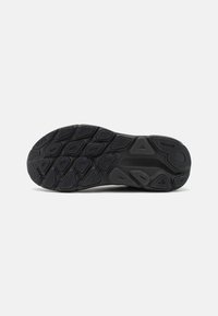Sole di sneaker nera caratterizzata da una superficie in gomma texturizzata con diversi motivi di battistrada per presa e stabilità; aree lisce e contorni definiti.
